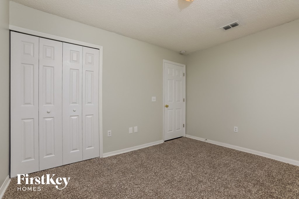 a bedroom with two closets and a carpeted floor