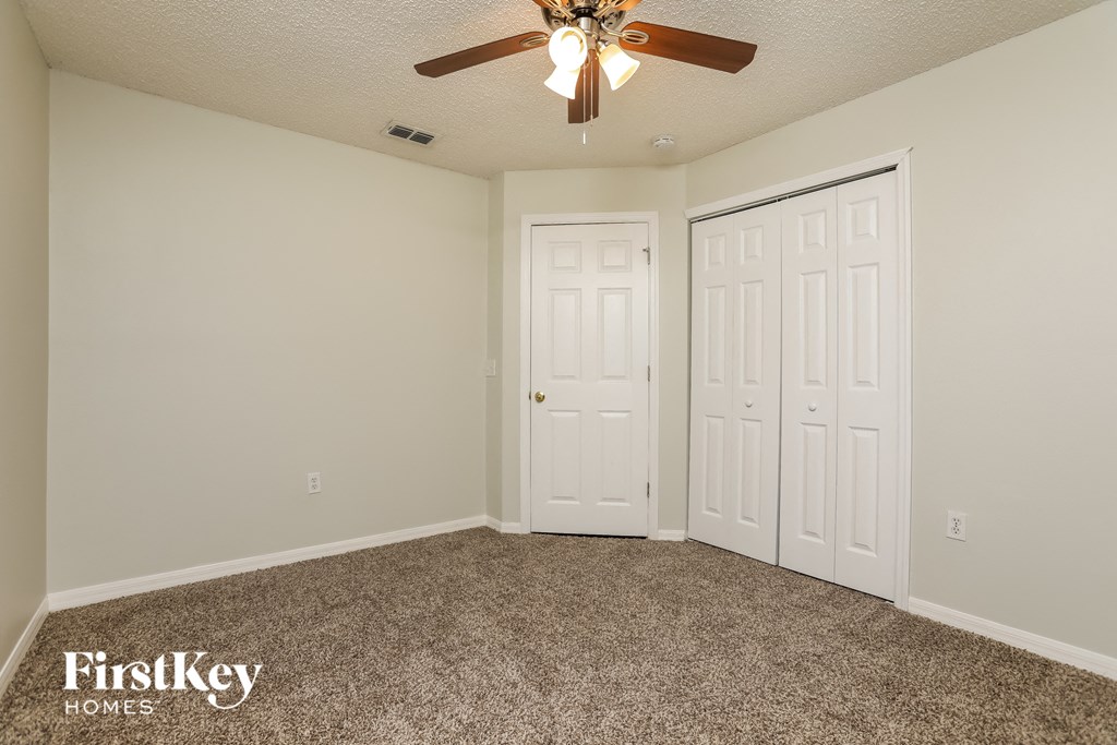 a bedroom with a ceiling fan and two closets