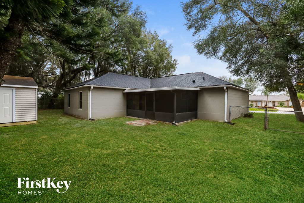 a view of the back of a house with a yard and trees
