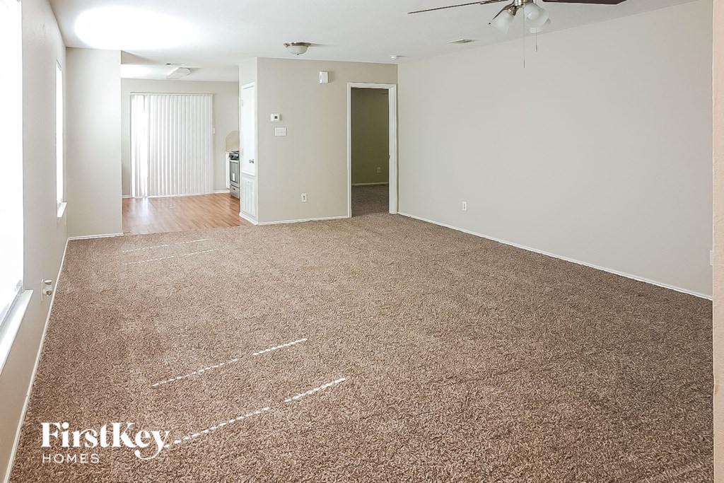 A spacious room with a carpeted floor and a ceiling fan.