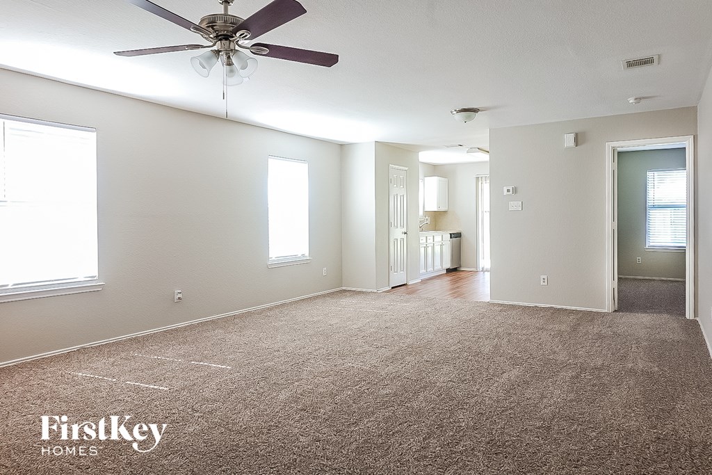 A spacious room with a carpeted floor and a ceiling fan.