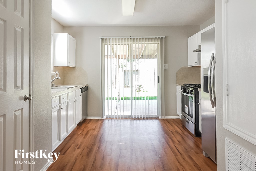 A kitchen with wooden floors and white cabinets.