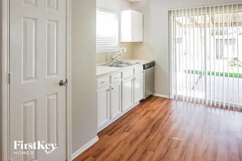 A kitchen with white cabinets and a white door.
