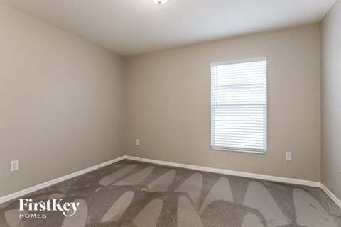 a bedroom with a window and a carpeted floor