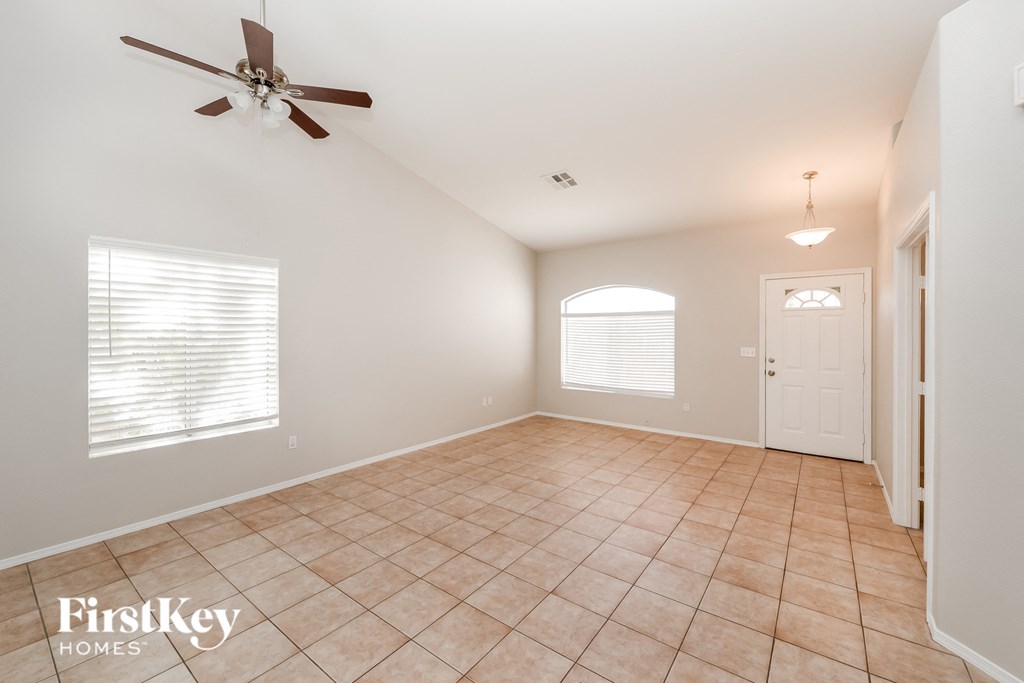 an empty living room with a ceiling fan and a tile floor