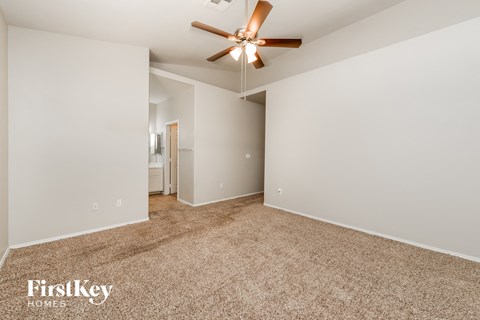 a spacious living room with carpet and a ceiling fan
