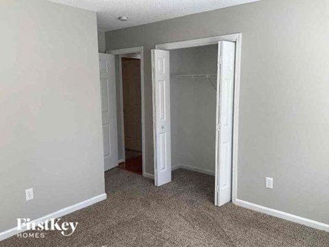 an empty bedroom with a closet and a door open