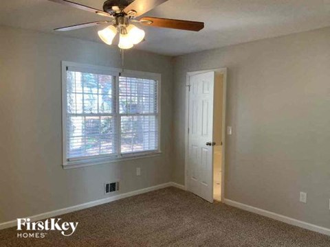 an empty bedroom with a ceiling fan and a window