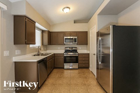 A kitchen with brown cabinets and a black refrigerator.