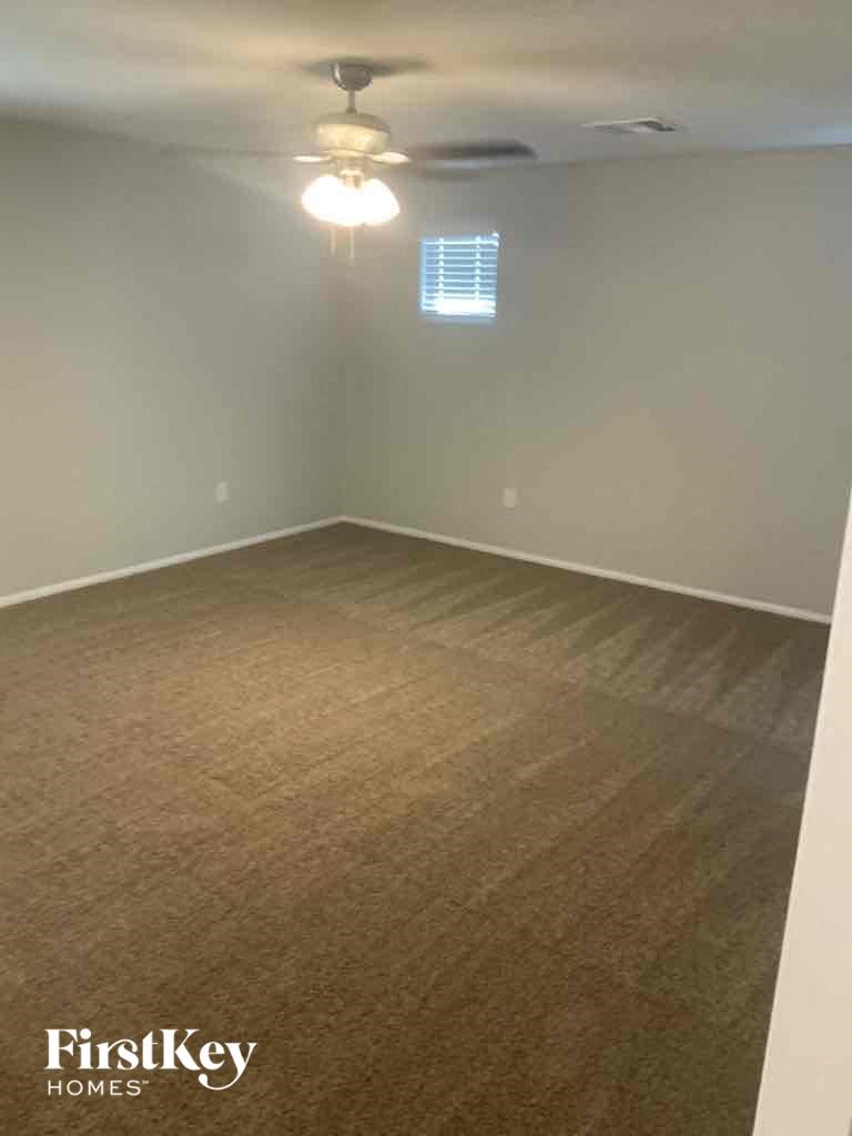 an empty living room with a ceiling fan and a window