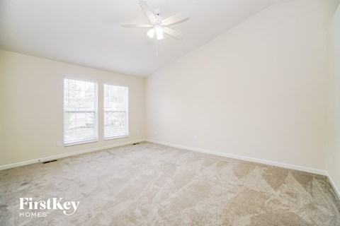 a bedroom with white walls and carpet and a ceiling fan