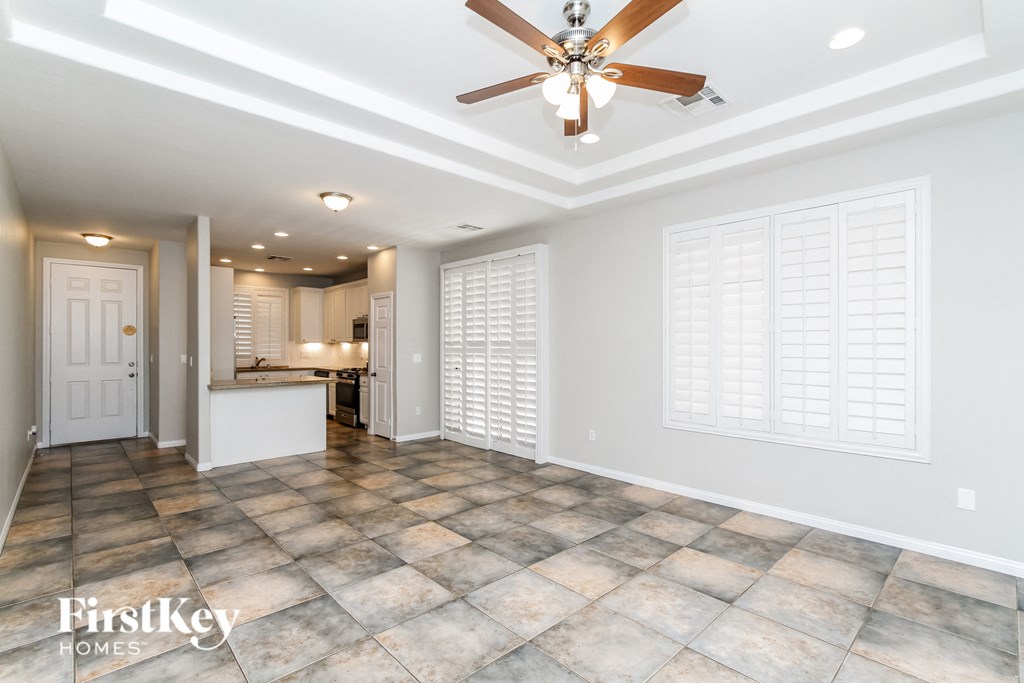 an empty living room with a ceiling fan and a kitchen