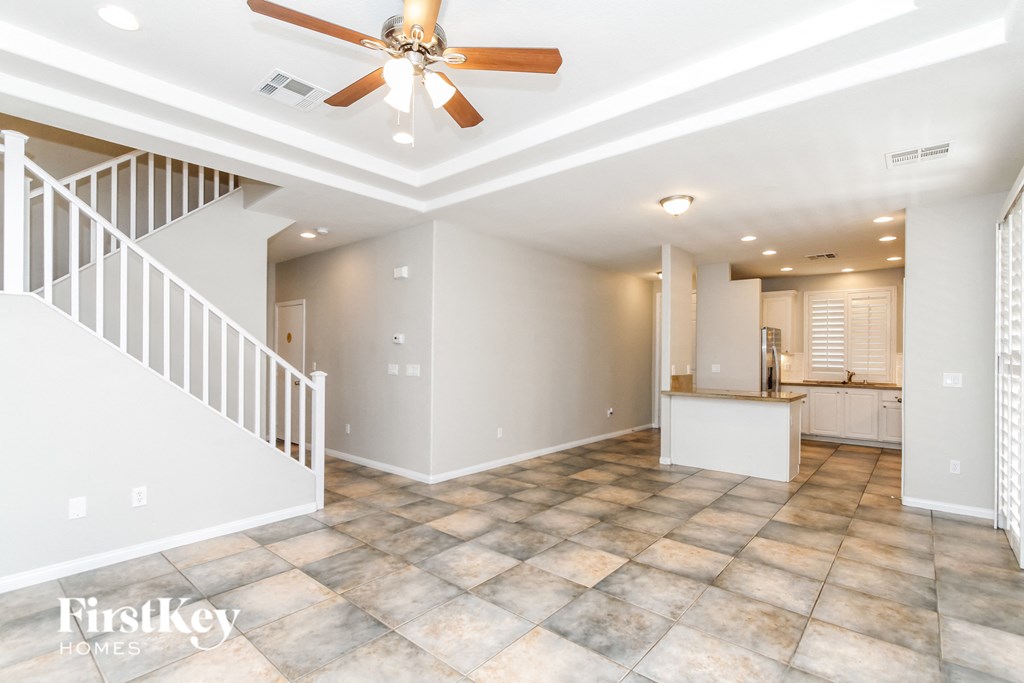 an empty living room with a ceiling fan and a staircase