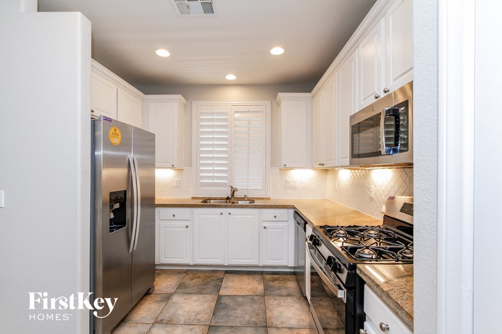 a kitchen with white cabinets and stainless steel appliances