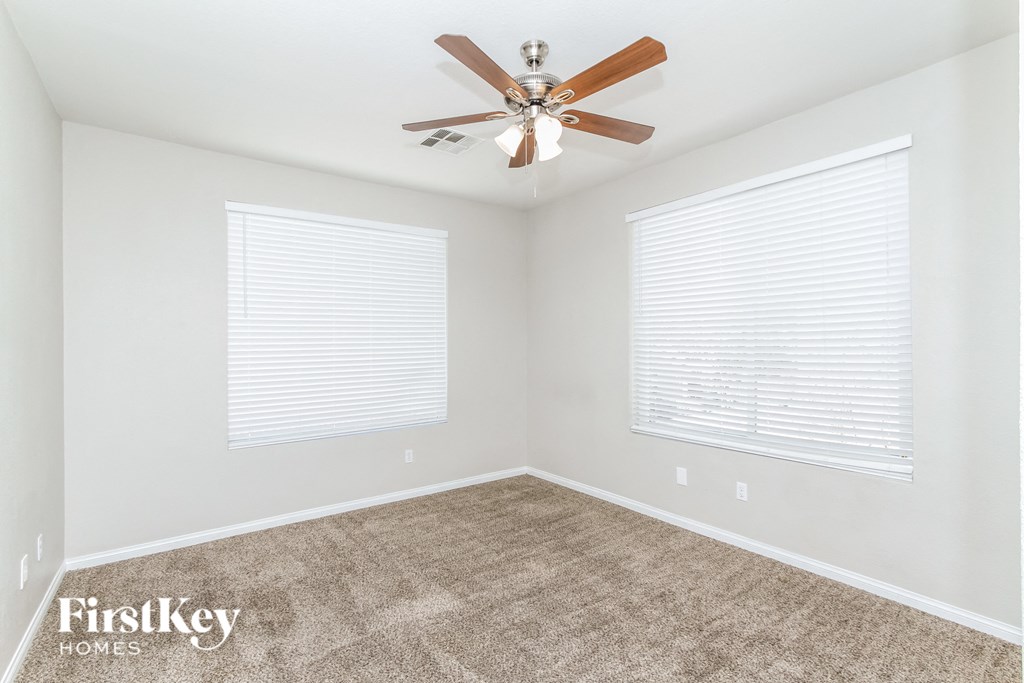 a living room with a ceiling fan and two windows