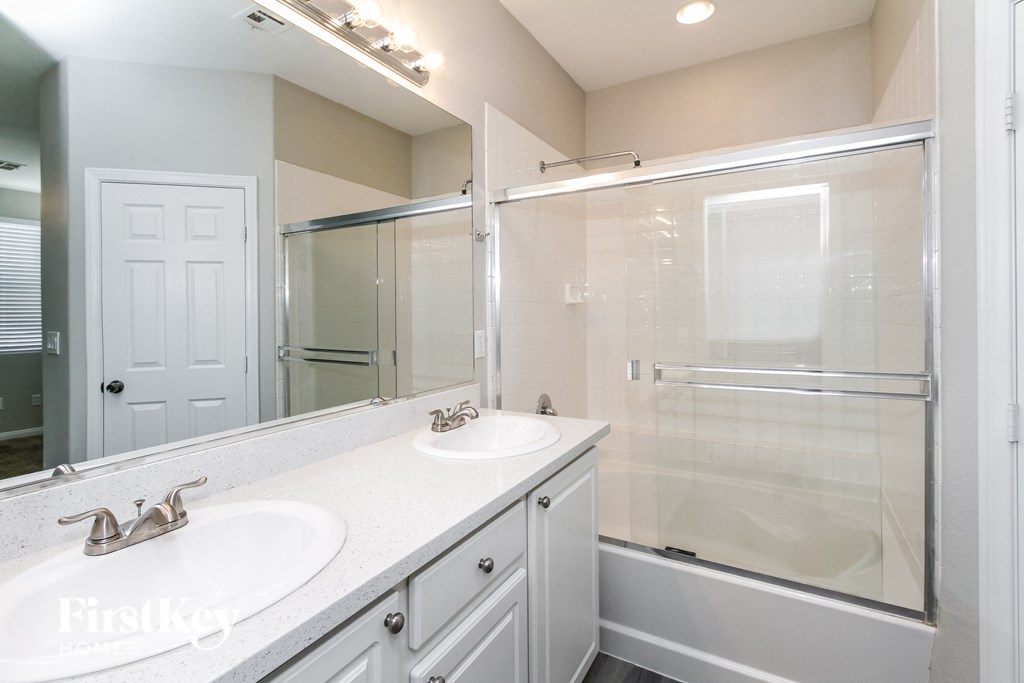 a bathroom with two sinks and a shower and a mirror