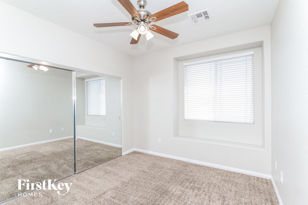 a bedroom with a ceiling fan and a mirrored closet