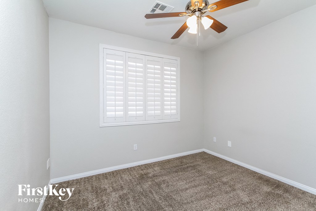 a empty room with a ceiling fan and a carpet