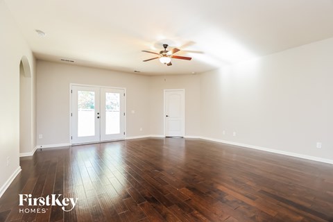 an empty living room with wood floors and a ceiling fan