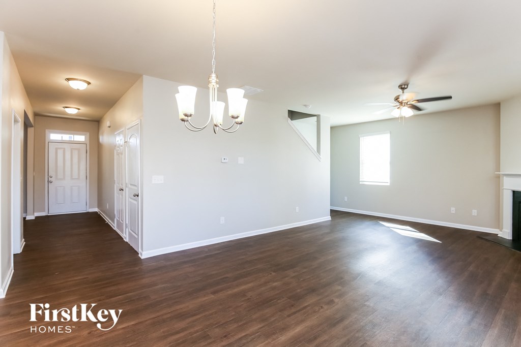 an empty living room with wood flooring and a ceiling fan