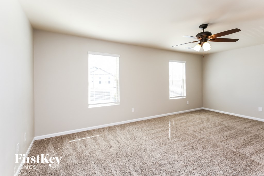 a bedroom with carpet and a ceiling fan and two windows