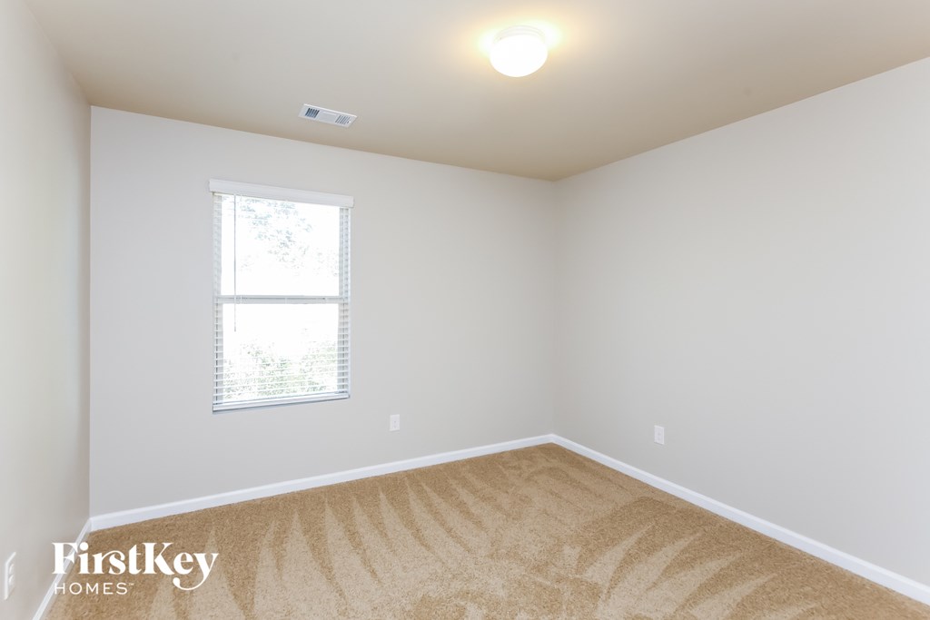 a bedroom with white walls and carpet and a window