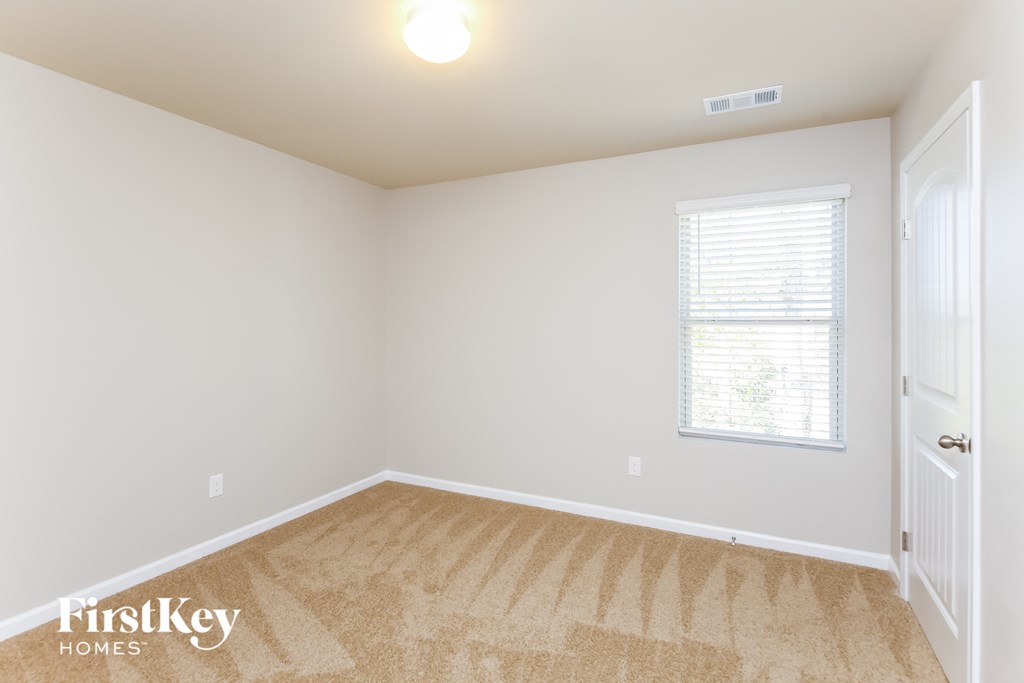 a bedroom with white walls and carpet and a window