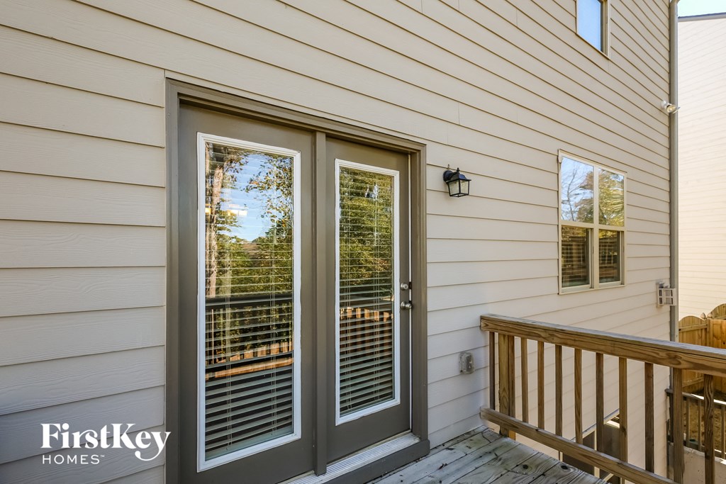 the deck off the back door of a house with sliding glass doors