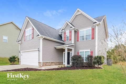 a home with a gray house with red shutters