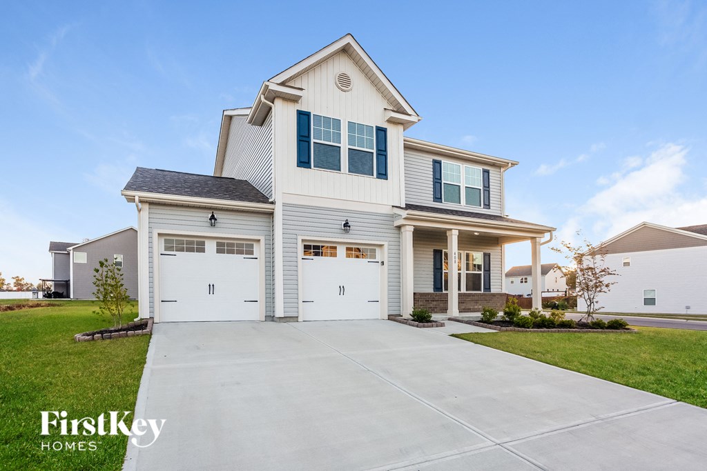 a white house with white garage doors and a driveway