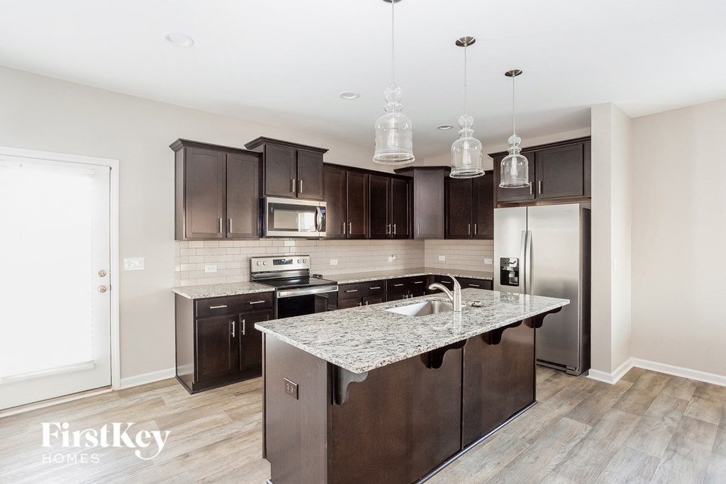 a kitchen with dark wood cabinets and a marble counter top