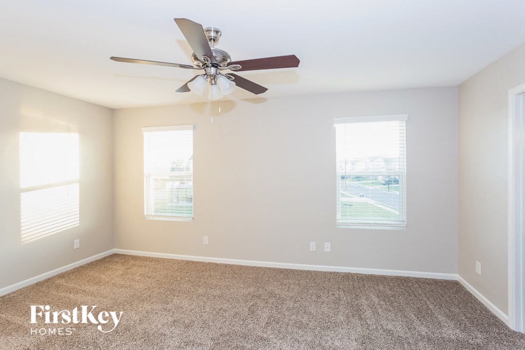 a empty room with a ceiling fan and two windows