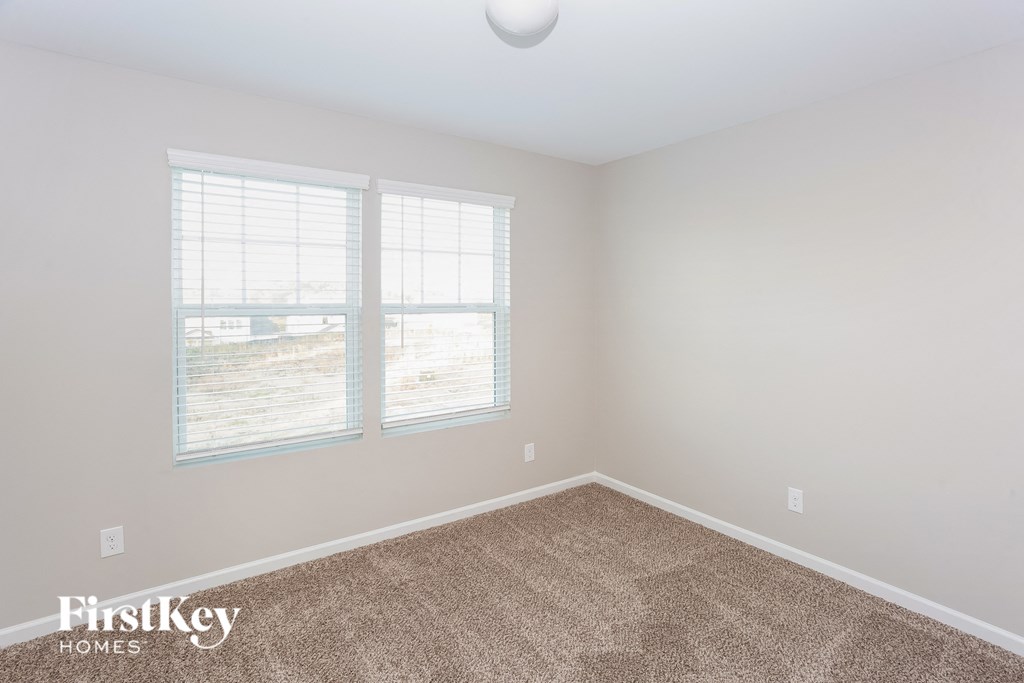 a bedroom with a carpeted floor and two windows