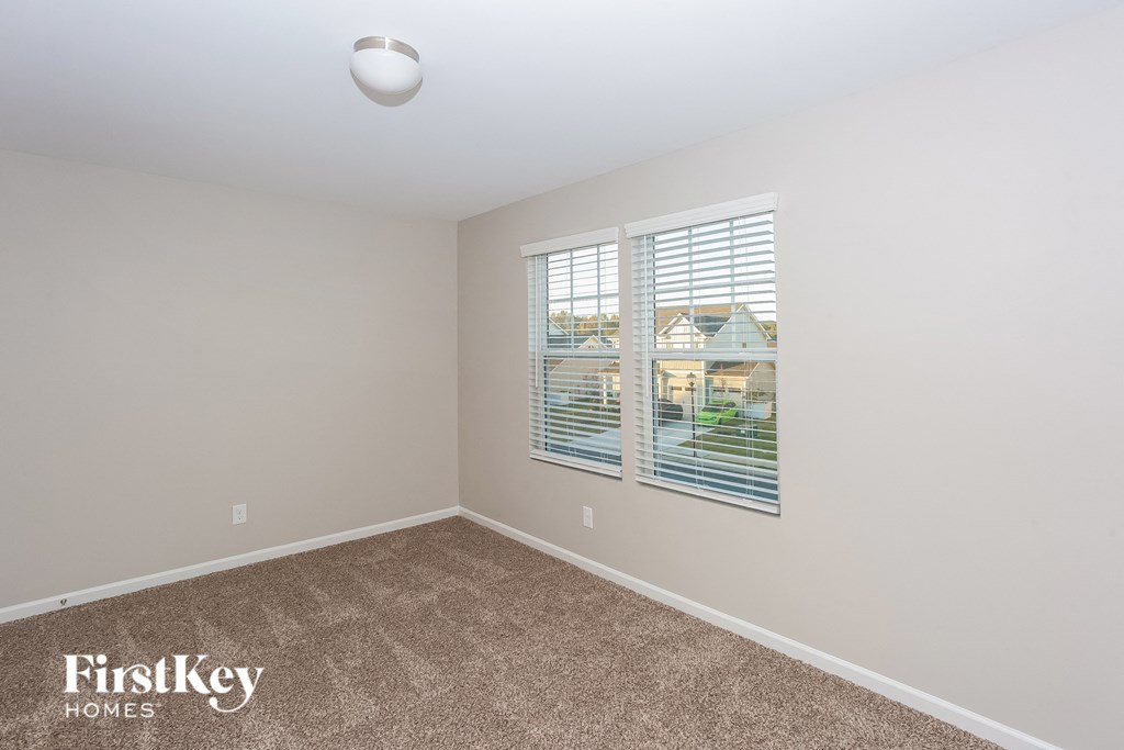 a spacious bedroom with carpeted flooring and a large window