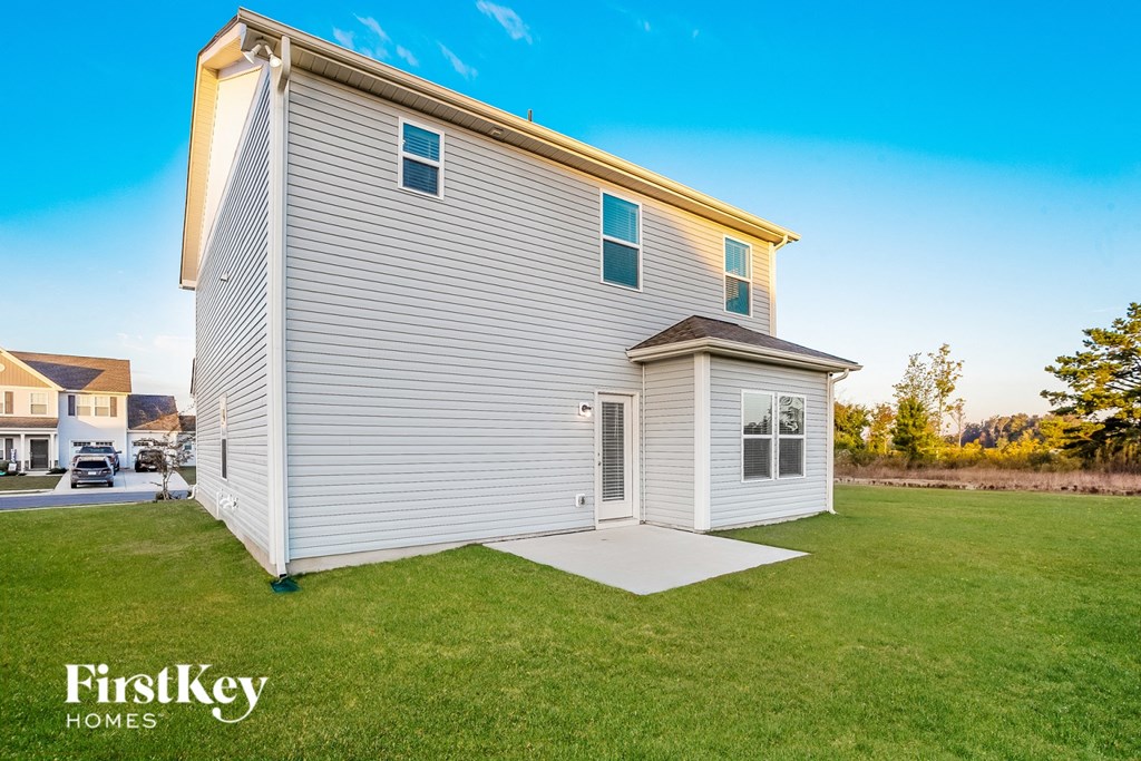 a small house with a white siding and a porch on the grass