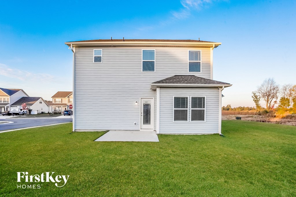 a small white house with a porch on a lawn