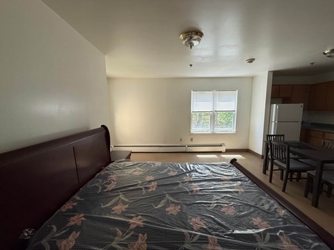A bedroom with a bed, table and chairs.