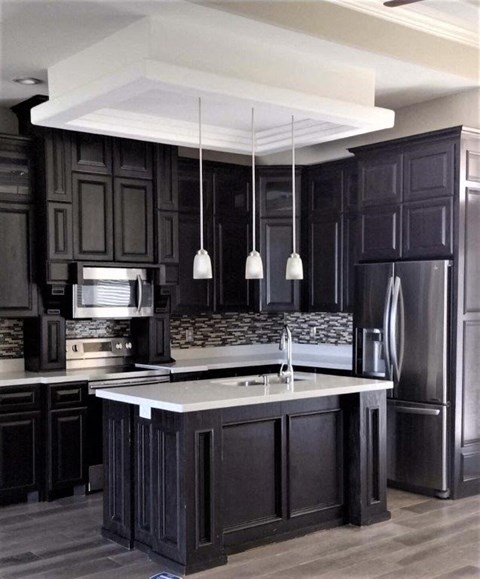 a large kitchen with black cabinets and a sink