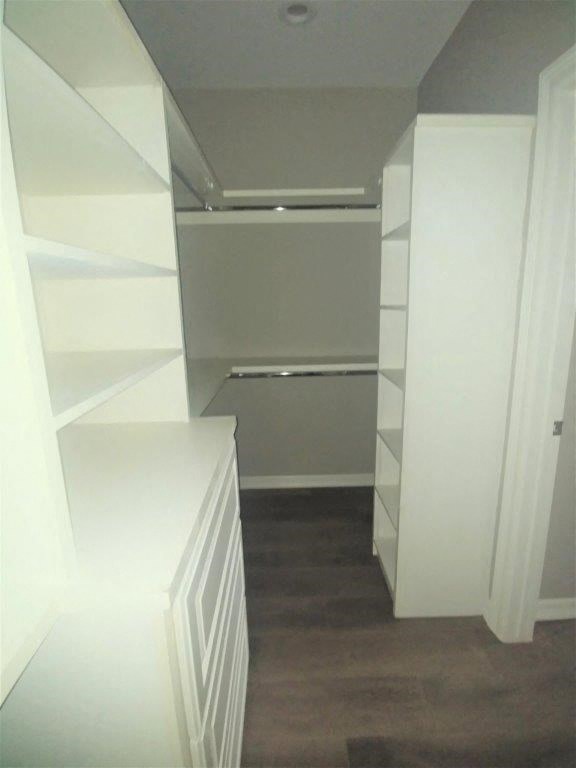 a closet with white shelves and a wood floor