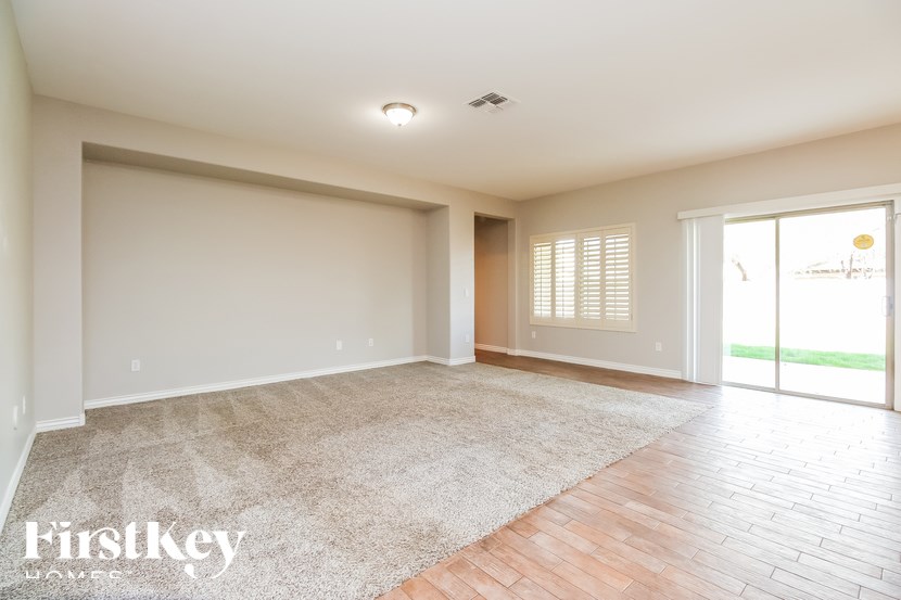 A spacious room with a carpeted floor and a sliding glass door leading to a balcony.