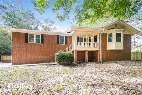 a brick house with a porch and a tree in front of it