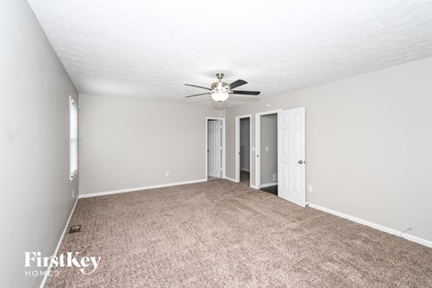a spacious living room with carpet and a ceiling fan
