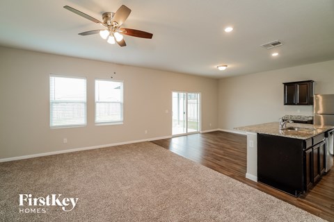 A spacious room with a kitchen area and a ceiling fan.
