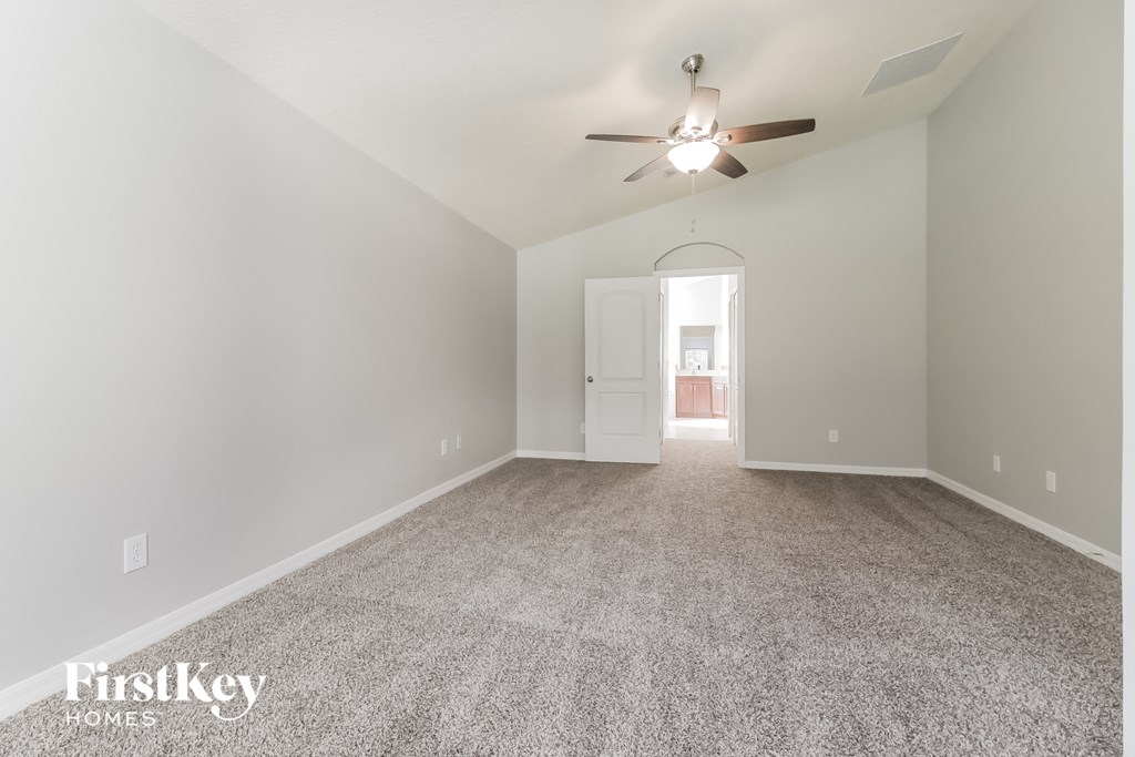 a spacious living room with carpet and a ceiling fan
