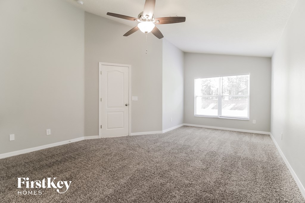 the spacious living room with ceiling fan and carpet