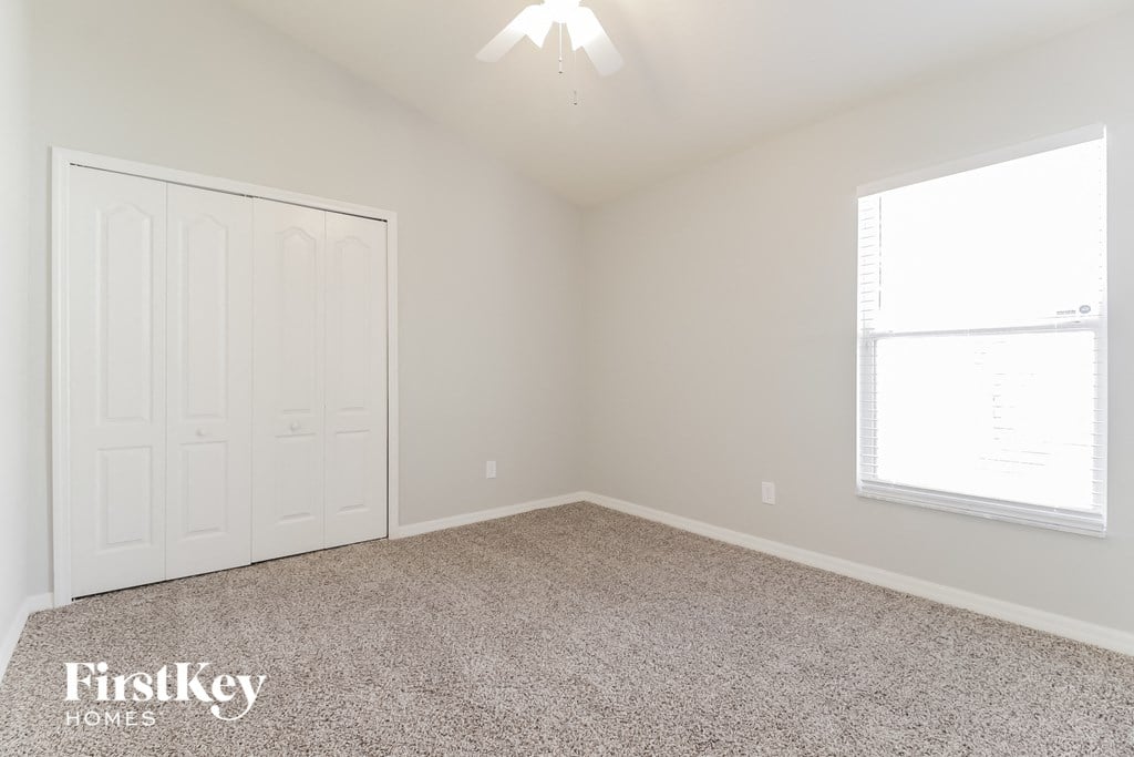 a bedroom with a carpeted floor and a white door and window