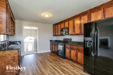 A kitchen with wooden cabinets and a black fridge.