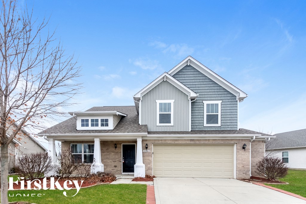 A house with a garage and a tree in front of it.