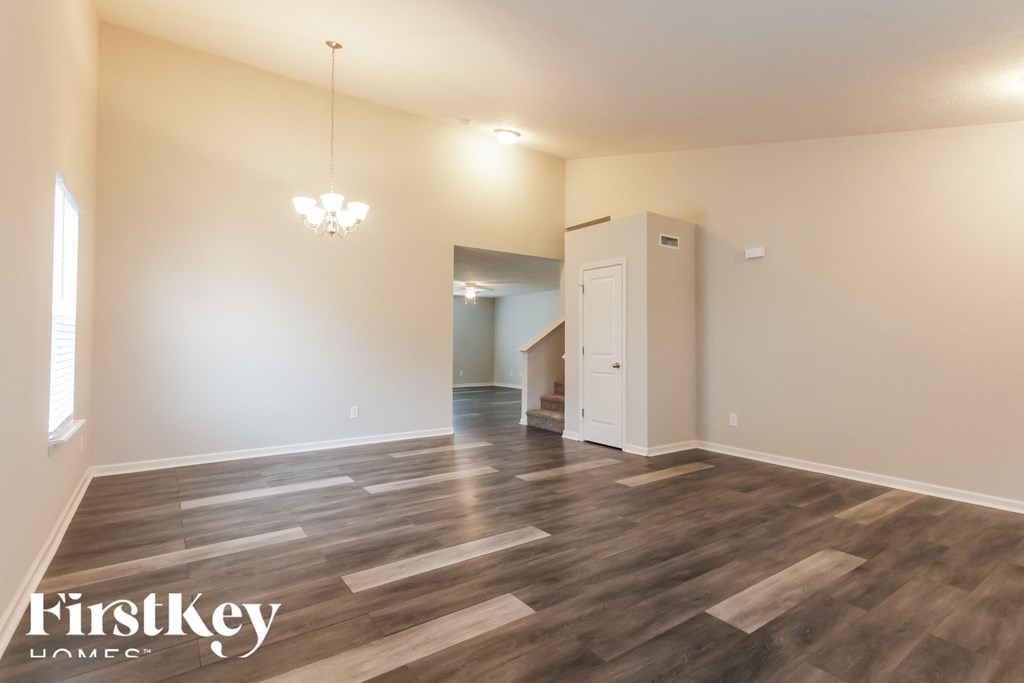 A large empty room with wooden floors and a chandelier.