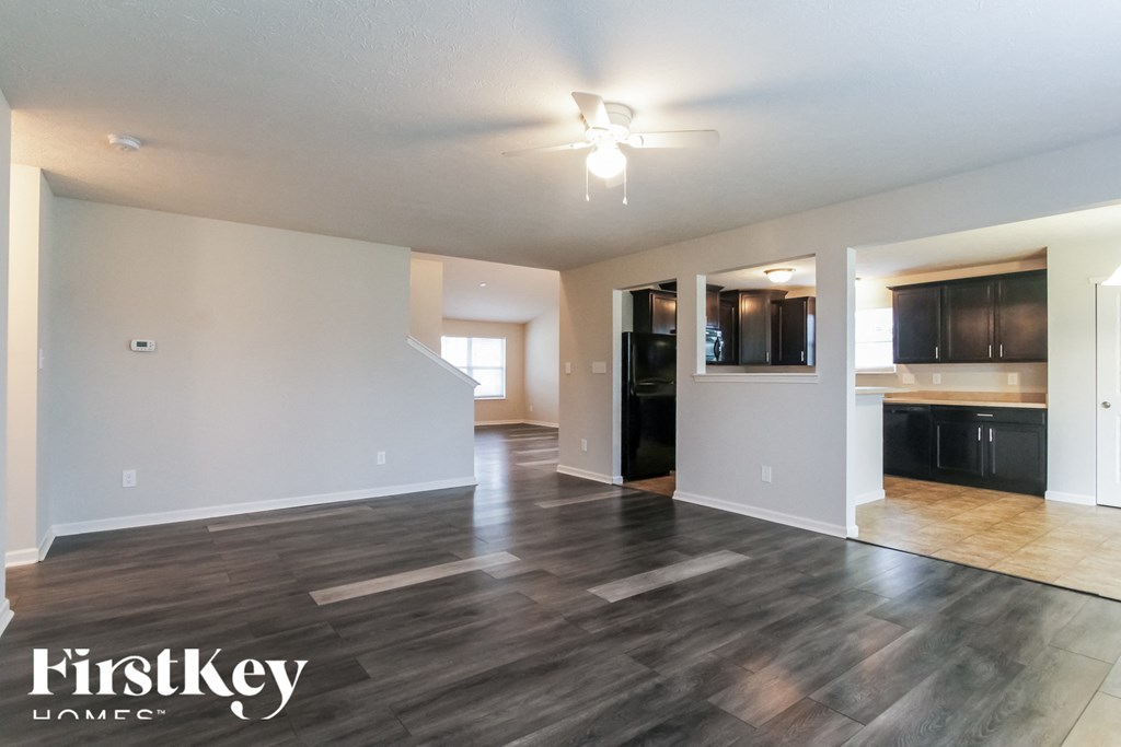 A spacious room with wooden flooring and a ceiling fan.